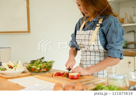 A woman cutting an apple in the kitchen 121873619