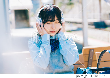 駅のホームで音楽を聴く女子高生 駅のホームで音楽を聴く女子高生 121873945