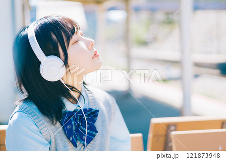 駅のホームで音楽を聴く女子高生 121873948