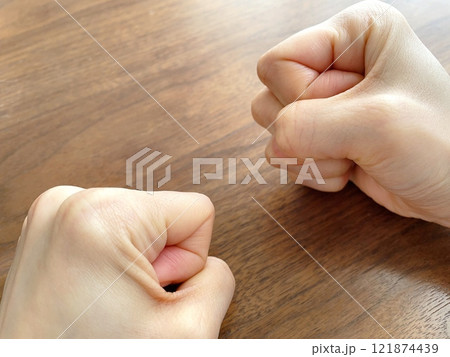 机上で拳を握りしめる女性の手元 121874439