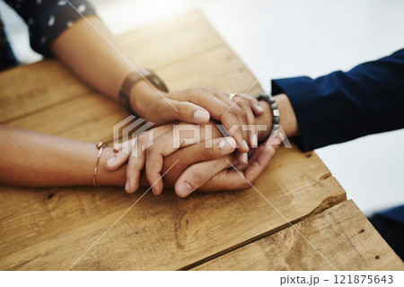 Hands holding abuse victim in a therapy session for support and comfort by a professional psychologist on a wooden table. Kind and caring therapist touching to show care and affection in counseling 121875643