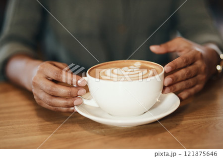Woman drinking coffee, sitting and relaxing in a cafe. Close up of an African lady with cappuccino, holding a cup at a restaurant table. Enjoying a hot beverage while on a break, taking time for rest Woman drinking coffee, sitting and relaxing in a cafe. Close up of an African lady with cappuccino, holding a cup at a restaurant table. Enjoying a hot beverage while on a break, taking time for rest 121875646