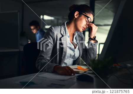 Stressed business woman working late on a computer in an office at night. Young worried entrepreneur feeling tired while struggling with burnout, eye strain and a headache from deadlines and pressure Stressed business woman working late on a computer in an office at night. Young worried entrepreneur feeling tired while struggling with burnout, eye strain and a headache from deadlines and pressure 121875765