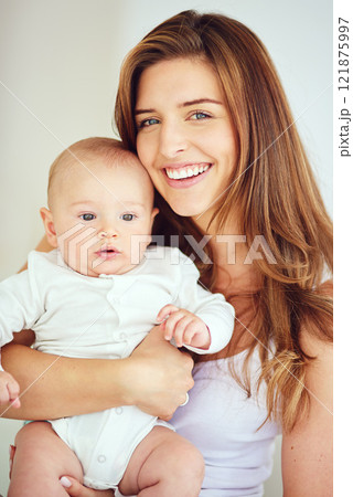 A beautiful, loving and caring mother holding baby, smiling and looking happy with new born. Single blonde parent or young mom showing love and care for her infant, bonding and smiling together 121875997