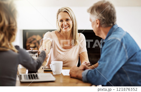 Financial advisor shaking hands with a female client after helping with budget, making a deal and planning with documents at home. Husband and wife paying for insurance and meeting with a consultant 121876352
