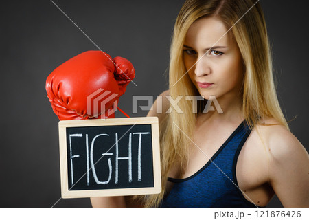 Woman wearing boxing glove holding fight sign Woman wearing boxing glove holding fight sign 121876426