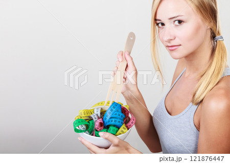 Diet. Girl with colorful measuring tapes in bowl Diet. Girl with colorful measuring tapes in bowl 121876447
