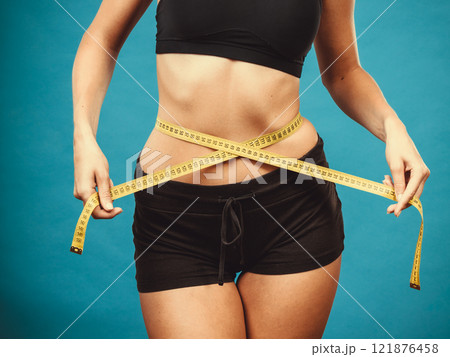 Fitness girl measuring her waistline Fitness girl measuring her waistline 121876458
