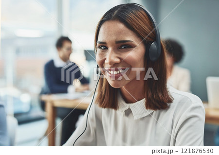 Customer service, IT support or call center agent helping and assisting on a call using a headset. Portrait of a young female sales assistant or secretary smiling while working in a modern office Customer service, IT support or call center agent helping and assisting on a call using a headset. Portrait of a young female sales assistant or secretary smiling while working in a modern office 121876530