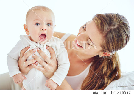 Happy, young and single mother bonding and taking care of adorable baby, enjoying parenthood and being a new mom. Happy female experiencing maternal instinct, holding cute, little child on a bed. 121876557