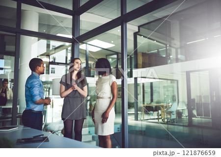 Business team standing and talking inside of the office together. Meeting and open discussion with colleagues in the workplace. Corporate mentor coaching and assisting new employees at the company. 121876659