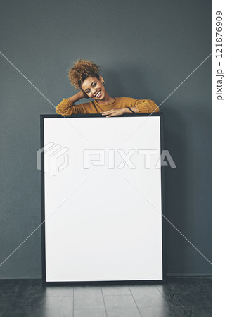 A beautiful confident woman holding a blank whiteboard or billboard sign with copy space. Happy and attractive female with a smile standing behind a banner. Young lady advertising with a poster A beautiful confident woman holding a blank whiteboard or billboard sign with copy space. Happy and attractive female with a smile standing behind a banner. Young lady advertising with a poster 121876909