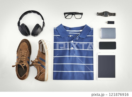 Flat lay of casual clothes, technology and shoes with a phone, tablet and headphones against background from above. All you need with a watch, USB stick and glasses for creative business workwear Flat lay of casual clothes, technology and shoes with a phone, tablet and headphones against background from above. All you need with a watch, USB stick and glasses for creative business workwear 121876916