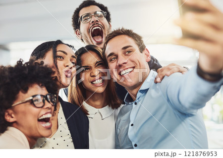Teamwork, playful and selfie while a group of cheerful businesspeople making funny faces together for a social media post. Faces of a happy and fun team standing together in a creative office Teamwork, playful and selfie while a group of cheerful businesspeople making funny faces together for a social media post. Faces of a happy and fun team standing together in a creative office 121876953