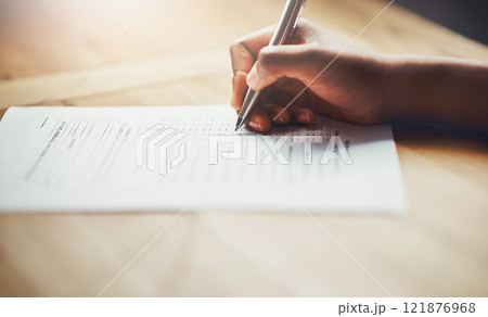 Closeup of business hands of a person filling out paperwork. Hand of an individual writing test, information or survey on paper to complete application or contract form on the desk at work. 121876968
