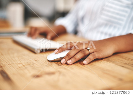 Hand on a mouse, clicking and scrolling while browsing online and surfing the internet. Closeup of a woman using a computer while sitting at a wooden desk. Connect with wireless bluetooth technology 121877060