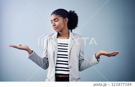 Decisions, choices and options with a young business woman comparing and weighing up different decisions with copyspace in studio against a grey background. Picking between two balanced ideas 121877184