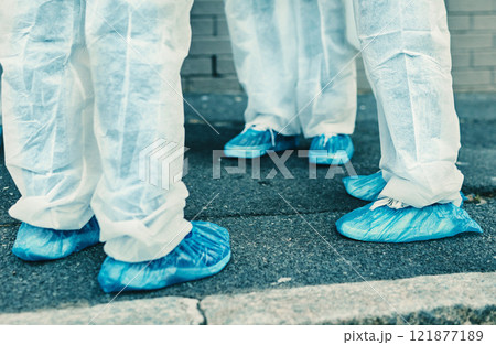 Legs and feet of healthcare workers wearing protective gear or hazmat suits outdoors while cleaning. Closeup of a team of medical professionals meeting during the covid or coronavirus pandemic Legs and feet of healthcare workers wearing protective gear or hazmat suits outdoors while cleaning. Closeup of a team of medical professionals meeting during the covid or coronavirus pandemic 121877189