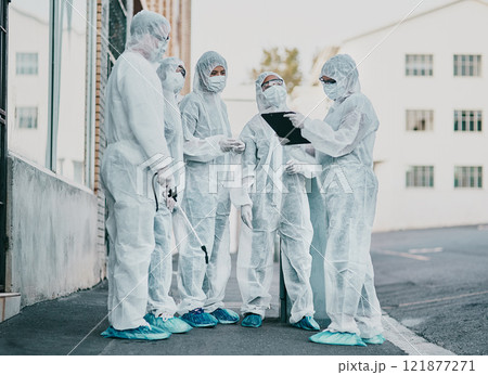 Covid, pandemic and healthcare team wearing protective ppe to prevent virus spread at a quarantine site. First responders wearing hazmat suits while discussing plan for cleaning and disinfecting 121877271