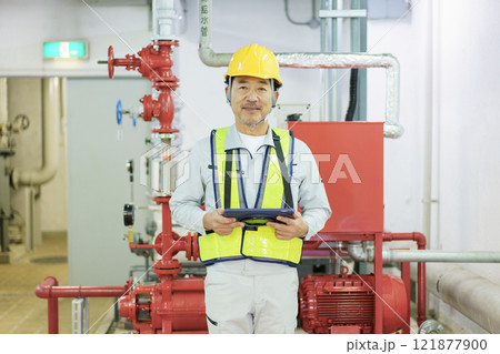 タブレットを持って立つ男性作業員　撮影協力：学校法人電波学園　東京電子専門学校 121877900
