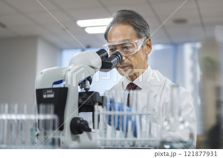 顕微鏡で作業をする白衣の男性研究員 121877931
