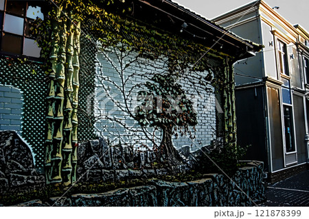 Beautifully decorated wall of the house. The wall design combines decorative elements in the form of a tree and natural climbing ivy. 121878399