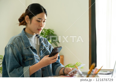 Young female architect uses smartphone to work. Young female architect uses smartphone to work. 121878729