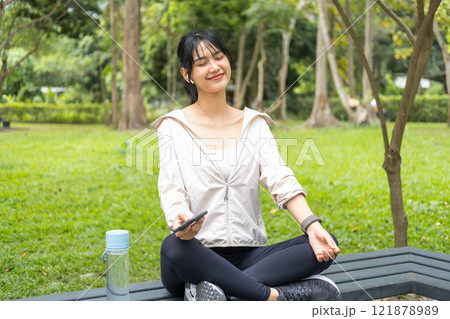 Young woman sitting and listening to music at the park. Young woman sitting and listening to music at the park. 121878989