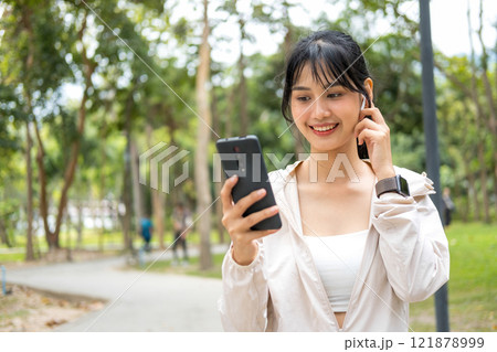 Young woman walking and listening to music at the park. Young woman walking and listening to music at the park. 121878999