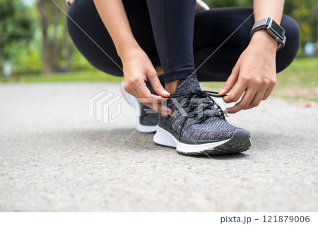Woman tying shoe laces at park. 121879006