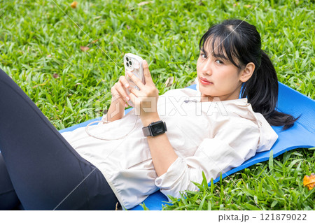 Young woman laying down on grass at park. 121879022