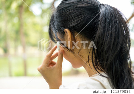 Young woman sitting and listening to music at the park. 121879052