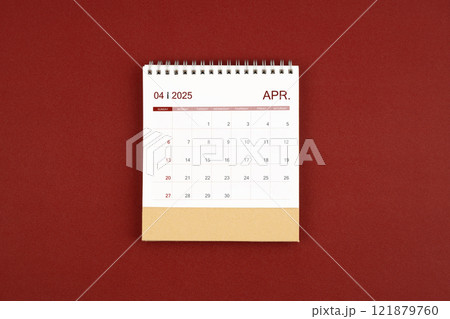 April 2025 desk calendar on red leather. 121879760