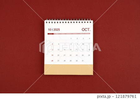 October 2025 desk calendar on red leather. 121879761