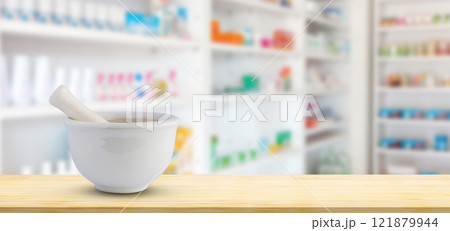 Mortar and pestle on pharmacy counter top with blur medicine shelves in drugstore background 121879944