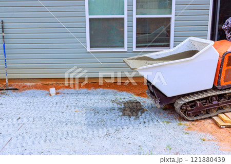 Rubber tracked dumper moves concrete for foundation slab to building under construction Rubber tracked dumper moves concrete for foundation slab to building under construction 121880439