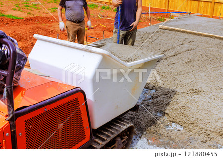 Workers are pouring fresh concrete using specialized rubber concrete truck at building site 121880455