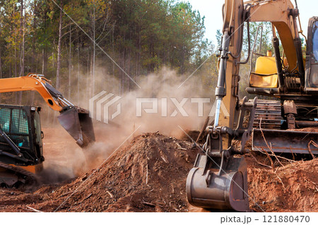 Bulldozers, excavators work together to clear trees, debris in forested area under at construction site Bulldozers, excavators work together to clear trees, debris in forested area under at construction site 121880470