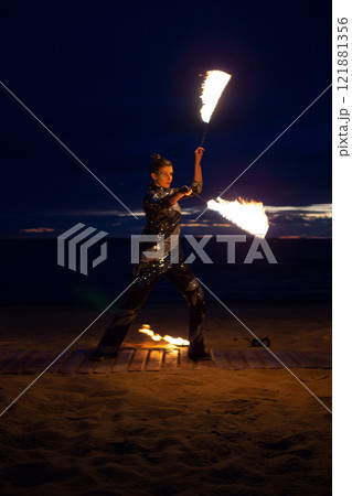 A girl lights a sparkler on the beach at dusk. A girl lights a sparkler on the beach at dusk. 121881356