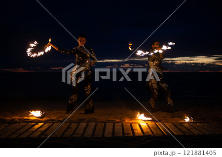 Two girls light a sparkler on the beach at dusk. 121881405