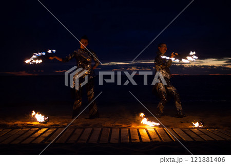 Two girls light a sparkler on the beach at dusk. 121881406