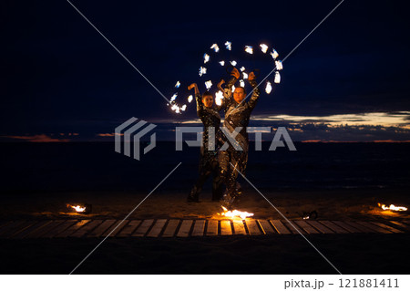 Two girls light a sparkler on the beach at dusk. Two girls light a sparkler on the beach at dusk. 121881411