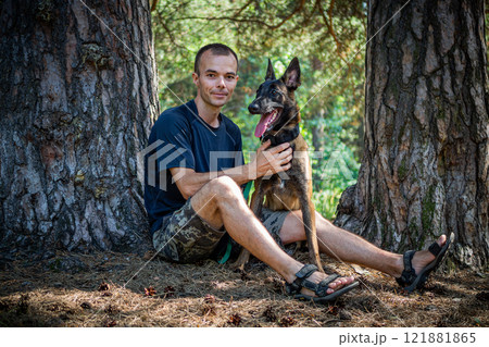 young Caucasian hipster spends time with his dog in the park on a sunny summer day. The concept of a pet as a family member 121881865