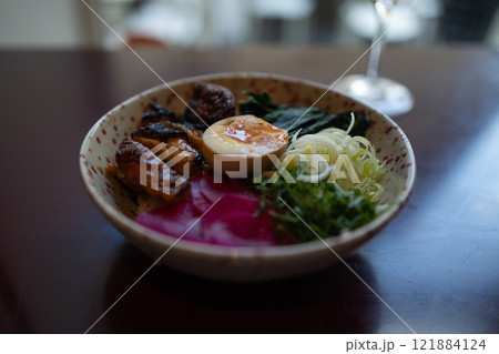 Japanese famous delicious ramen with different ingredients Noodle soup with shiitake, egg and pak choi cabbage on dark background. Japanese famous delicious ramen with different ingredients Noodle soup with shiitake, egg and pak choi cabbage on dark background. 121884124
