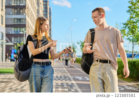 Guy and girl, college students walking together along street of city Guy and girl, college students walking together along street of city 121885581