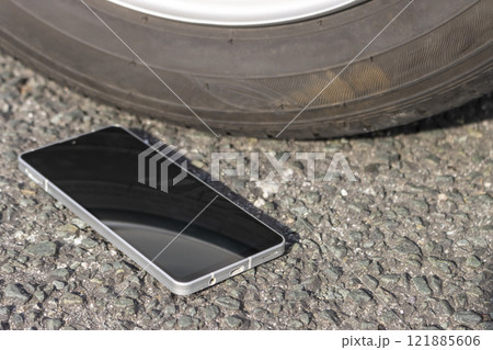 車のタイヤの横に落ちたスマートフォン 121885606