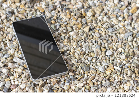 小石の道に落ちたスマートフォン 121885624