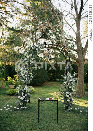 A table sits beneath a tree in the center of green grass 121886135