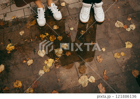A few people standing in a puddle of water with leaves around 121886136