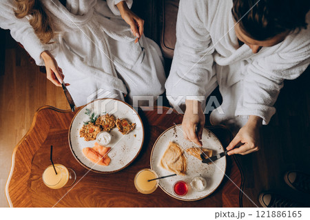 A man and a woman are sitting together at a table enjoying their food A man and a woman are sitting together at a table enjoying their food 121886165